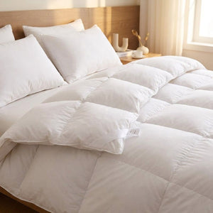 Couette blanche moelleuse sur un lit fait avec oreillers dans une chambre chaleureuse