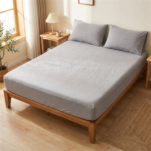 Drap housse en coton percale gris uni installé sur un lit dans une chambre lumineuse et cosy
