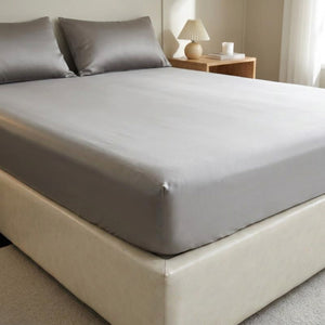 Drap housse gris en soie installé sur un lit dans une chambre élégante et lumineuse