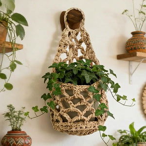 Panier suspendu en macramé de coton avec lierre vert sur mur dans salon bohème naturel