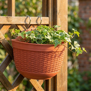 Pot de fleur mural en imitation rotin terracotta avec lierre vert sur treillis bois