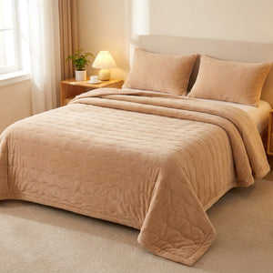 Couvre-lit matelassé uni beige posé sur un lit dans une chambre chaleureuse