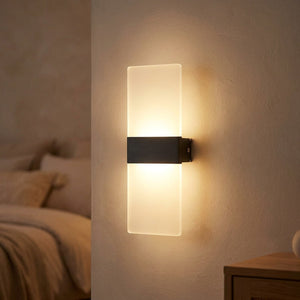Applique murale LED noire au panneau acrylique diffusant une lumière chaude haut et bas sur un mur