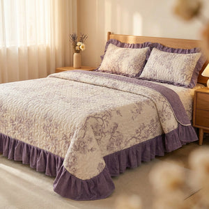 Couvre-lit matelassé à volants au motif floral violet installé sur un lit dans une chambre lumineuse