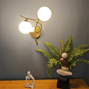 Applique murale dorée dans un intérieur avec plante et sculpture