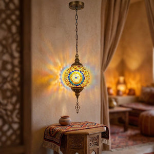 Suspension en mosaïque de verre style marocain allumée suspendue au plafond diffusant une lumière kaléidoscopique ambrée dans un intérieur bohème