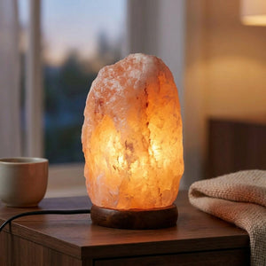 Lampe de sel de l'Himalaya allumée posée sur une table de chevet en bois