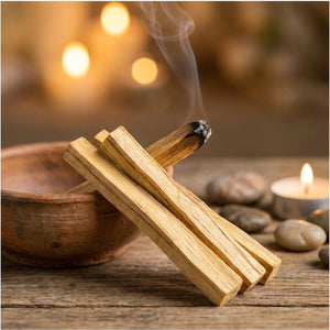 Bâtons d'encens Palo Santo allumés dans un bol en argile sur surface en bois avec pierres et bougie