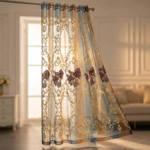 Rideau voilage tulle brodé de fleurs dégradé bleu et marron accroché à une fenêtre lumineuse