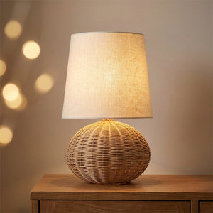 Lampe à poser en rotin tressé forme ronde avec abat-jour beige allumée