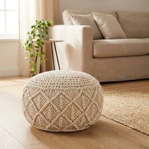 Pouf en macramé rond de couleur crème posé au sol dans un salon bohème lumineux près d'un canapé