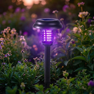 Lampe anti-moustiques solaire de jardin avec lumière UV violette dans un massif fleuri au crépuscule