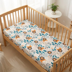 Drap housse bébé motif lionceaux colorés installé sur un matelas de berceau en bois