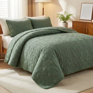 Couvre-lit matelassé vert sauge avec taies d'oreiller posé sur un lit dans une chambre lumineuse