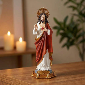 Statue du Sacré-Cœur de Jésus en résine peinte posée sur une console en bois éclairée par des bougies