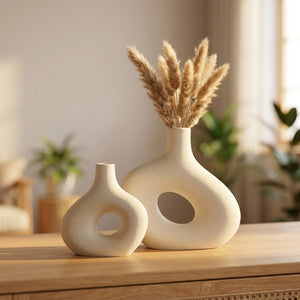 Deux vases en céramique donut blanc cassé garnis de pampa sur une console en bois