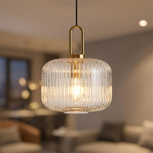 Suspension en verre transparent cannelé avec anse en métal doré au-dessus d'une table