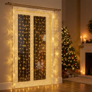 Rideau lumineux LED avec fils cuivrés suspendu à une tringle dans une fenêtre décorée pour Noël