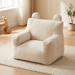 Fauteuil enfant moelleux écru aux oreilles arrondies posé dans une chambre lumineuse