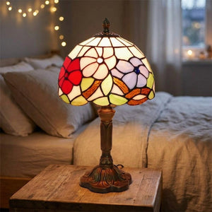 Lampe de chevet style Tiffany à abat-jour en vitrail fleuri posée sur une table de chevet