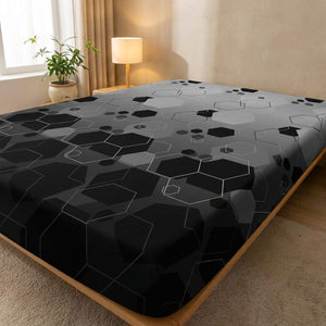 Drap-housse imprimé à motif hexagones géométriques noir et gris tendu sur un lit