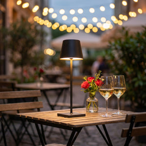 Lampe LED tactile noire silhouette conique allumée sur une table de bistrot