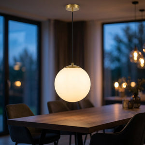 Suspension boule de verre dépolie dorée allumée au-dessus d'une table à manger