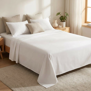 Drap plat blanc en coton égyptien posé sur un lit fait dans une chambre lumineuse