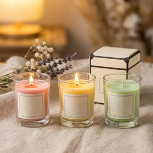 Bougies parfumées colorées en cire de soja allumées près de leur coffret cadeau dans une ambiance cosy