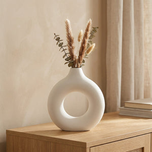 Vase à fleurs anneau blanc au design scandinave avec pampa séchée posé sur une console en bois
