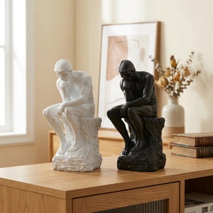 Statue Le Penseur de Rodin en résine blanche et noire posée sur une console en bois