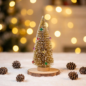 Sapin de Noël miniature doré pailleté sur socle en bois sur une table de fête enneigée