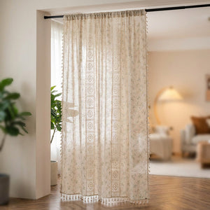 Rideau bohème crème aux motifs fleuris et bandes de dentelle au crochet suspendu devant une fenêtre lumineuse