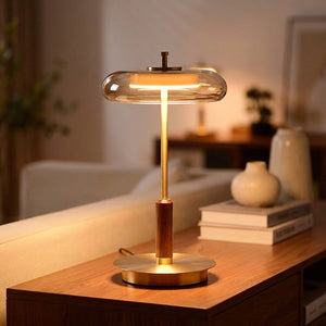 Lampe vintage à poser en laiton et noyer abat-jour verre ambré allumée sur un meuble