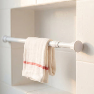 Tringle extensible blanche fine installée dans une niche de douche carrelée