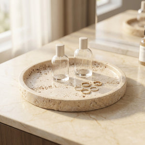 Plateau décoratif rond en pierre travertin beige avec parfums et bagues sur une coiffeuse