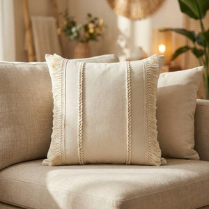 Housse de coussin bohème beige tissée à franges posée sur un canapé en lin