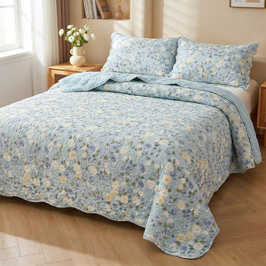 Couvre-lit matelassé floral bleu à motif de roses sur un lit dans une chambre lumineuse