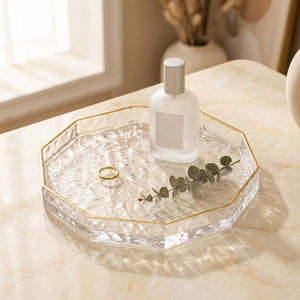 Plateau en verre à facettes au bord doré avec parfum et bijou sur une coiffeuse en marbre