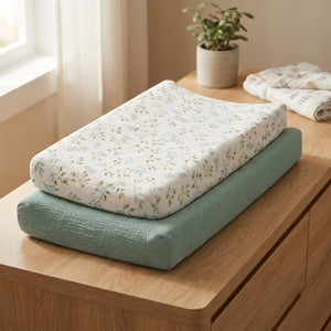Housse de matelas à langer en mousseline de coton fleurs sauge posée sur une commode en bois dans une chambre bébé lumineuse