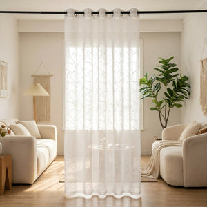 Voilage blanc à motif géométrique brodé suspendu à une fenêtre dans un salon lumineux