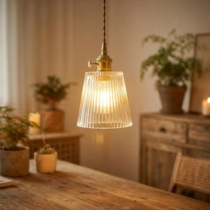 Suspension en verre strié transparent laiton doré allumée au-dessus d'un plan de travail, ambiance vintage nordique chaleureuse