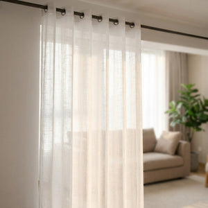 Voilage transparent en tulle blanc à œillets suspendu devant une fenêtre lumineuse dans un salon