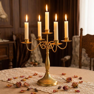 Chandelier en métal doré à cinq branches avec bougies allumées sur une table de fête