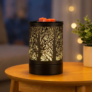 Brûle-parfum électrique noir au motif forêt avec lumière LED colorée allumée sur une table