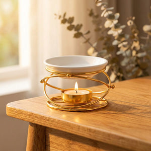 Brûle-parfum doré avec bougie allumée et bol en céramique sur table en bois