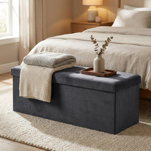 Banc coffre de rangement pliable en velours gris capitonné au pied d'un lit