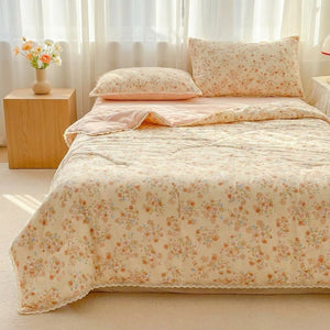 Couette d'été à imprimé floral rose et bordure en dentelle posée sur un lit dans une chambre lumineuse