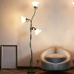 Lampadaire fleur 3 têtes allumé dans un salon avec fauteuil
