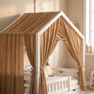 Ciel de lit cabane en mousseline marron camel drapé sur un lit cabane blanc